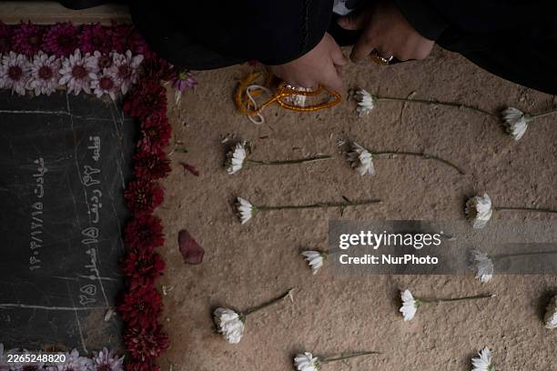 Young veiled Iranian woman prays as she sits beside a grave of her relative who is killed during the U.S.-Israeli military campaign, at Behesht-e...