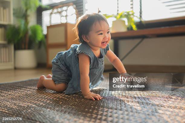happy toddler girl crawling on a rug in a bright modern living room at home, capturing joyful childhood development, early learning movement, and warm family lifestyle. - crawling stock pictures, royalty-free photos & images