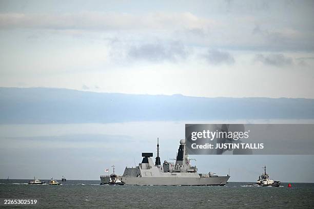 Dragon, a Royal Navy Type 45 Daring-class air-defence destroyer warship, is guided by tug boats operated by Serco Marine Services, as departs from HM...