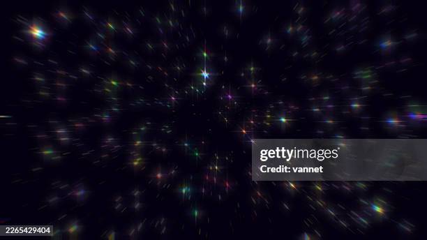 Numerous vibrant, glittering specks of light burst across a deep, dark expanse
