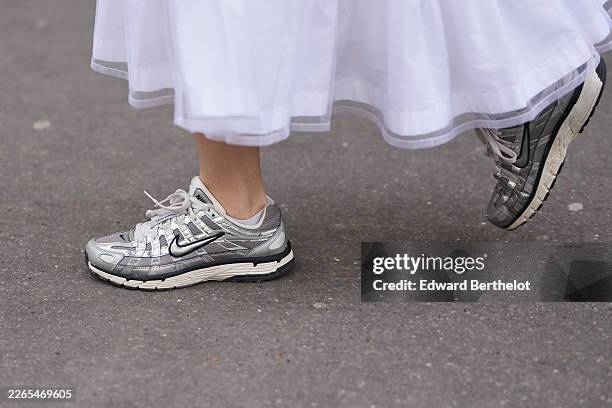 Guest wears a white cotton tiered midi skirt, gray mesh and leather sneakers from Nike, outside Noir Kei Ninomiya, during Paris Fashion Week -...