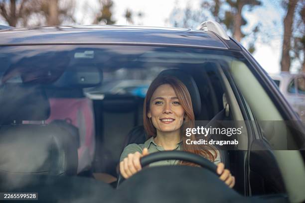 woman driving car smiling feeling happy and independent - drivers seat stock pictures, royalty-free photos & images