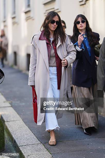 Guest wears long straight dark brown hair with a center part, black rectangular sunglasses, a red leather tote bag, a light beige trench coat with...