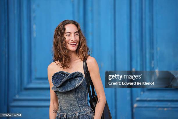 Guest wears a blue denim strapless / shoulder off with embroidered ruffled panel fitted corset, matching blue denim ballon wide legs pants, a black...