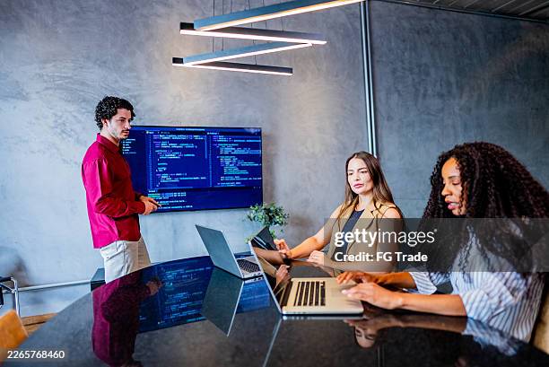 coworkers talking while programming on laptop at office - html stock pictures, royalty-free photos & images