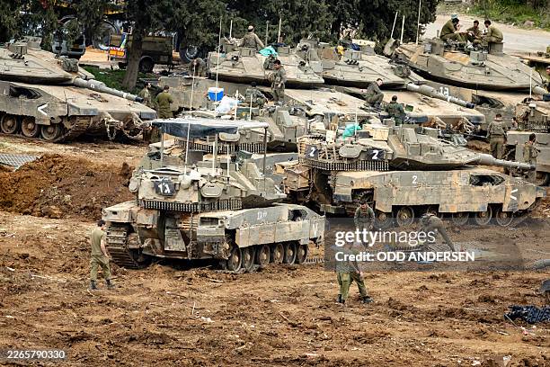 Israeli soldiers work on the belts for their tanks at a staging area in the Upper Galilee in northern Israel near the border with Lebanon on March...