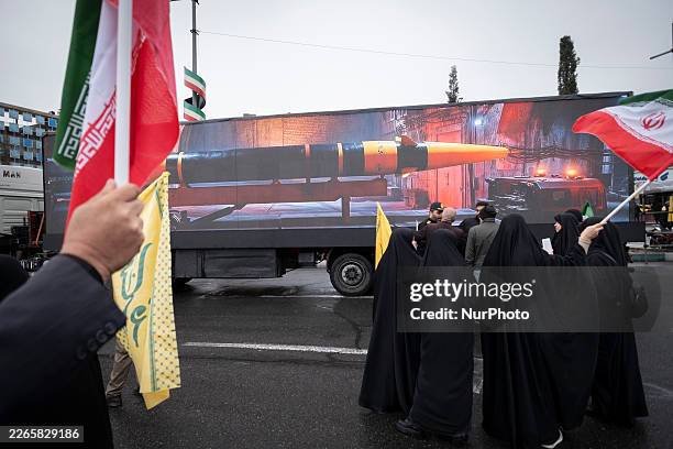 Veiled Iranian women gather in front of a display featuring an image of an Iranian-made ballistic missile while participating in a rally...