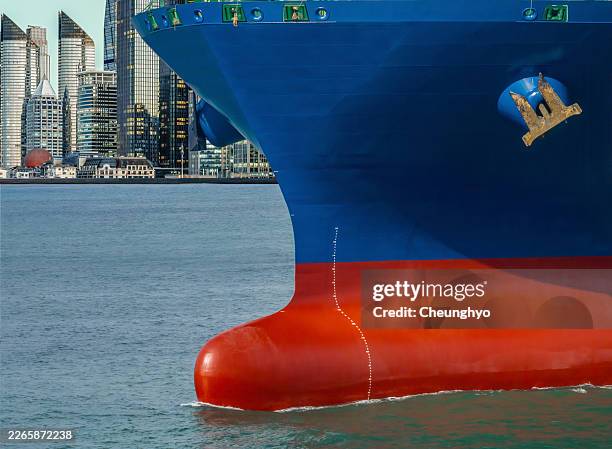 an new container ship is sailing in front of qingdao city skyline at dusk - schiffsbug stock-fotos und bilder