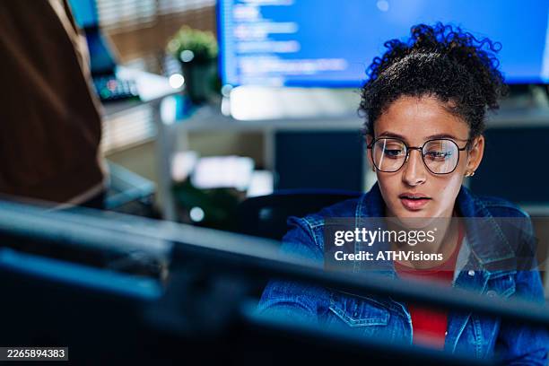 young latina software developer analyzing code on computer screen - application developer stock pictures, royalty-free photos & images