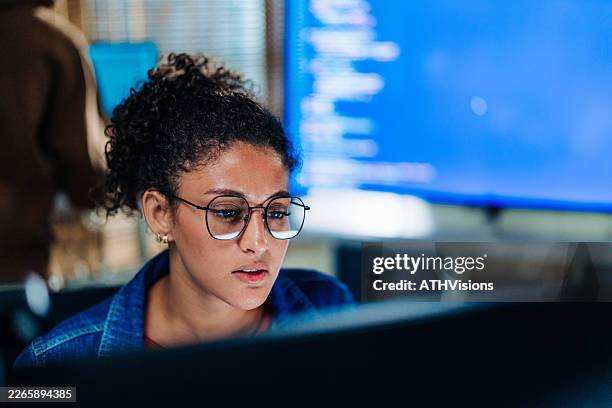 focused hispanic female programmer working at computer in tech office - multiple screens stock pictures, royalty-free photos & images