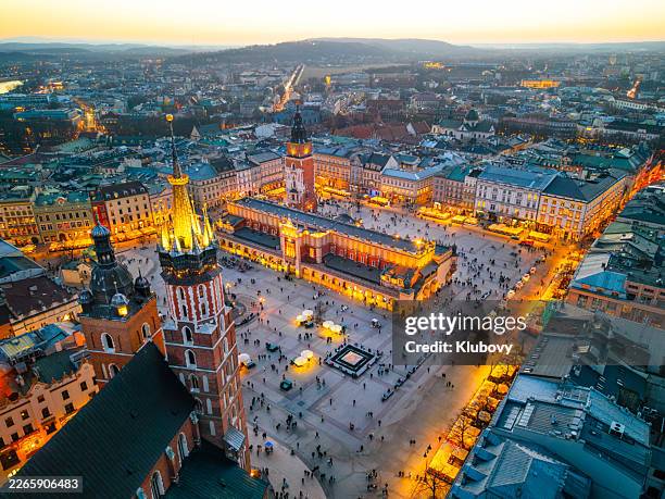 vista aérea de la plaza del mercado mayor iluminada y la basílica de santa maría en cracovia, polonia, al anochecer - cracovia fotografías e imágenes de stock