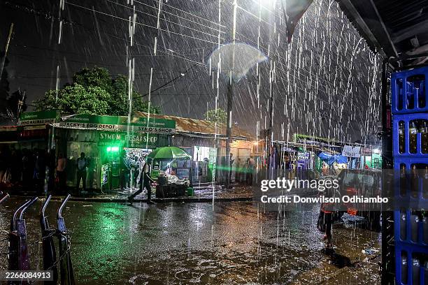 Residents hide under street shops from heavy rains in the Kibera Slums on March 14, 2026 in Nairobi, Kenya. At least 25 people have died after heavy...