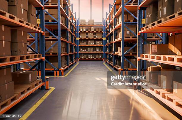 package distribution warehouse aisle with stacked boxes on pallets and industrial shelving in warm light - road marking stock pictures, royalty-free photos & images