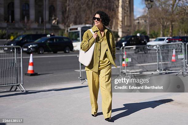 Guest wears black sunglasses, a green olive suede button front jacket, a yellow chartreuse knit polo shirt, matching yellow chartreuse wide leg...