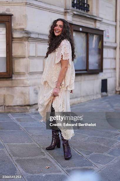 Guest wears brown wavy hair, a cream lace short sleeve ruffled long blouse dress, dark brown leather knee-high boots, outside Zimmermann, during...