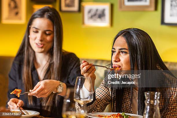 friends eating pasta at restaurant table enjoying dinner and wine conversation - tomato pasta stock pictures, royalty-free photos & images