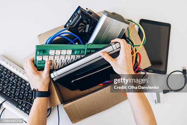 person sorting old electronic devices and cables into a recycling box - old electronics stock pictures, royalty-free photos & images