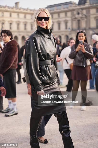 Poppy Delevingne wears black squared sunglasses, a black leather high neck / belted coat, a black leather pencil skirt, outside Elie Saab, during...