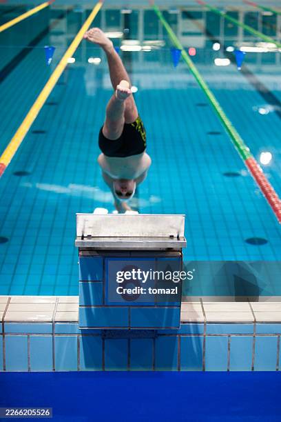 male swimmer diving off starting block number 6 into pool - swimming starting block stock pictures, royalty-free photos & images