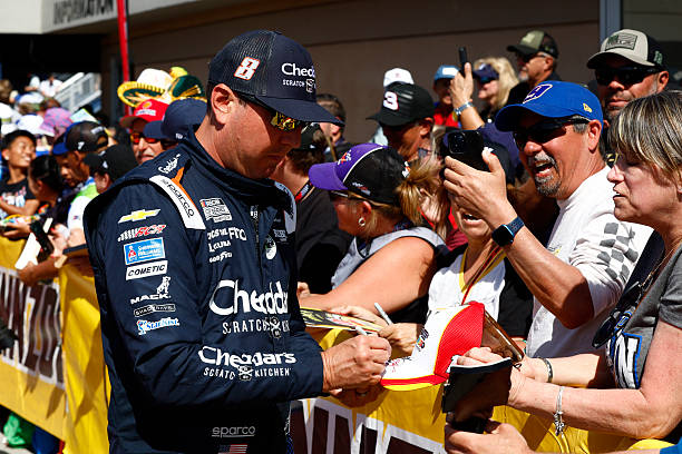 Kyle Busch signs an autograph prior to the drivers meeting in the Neon Garage before the start of the Pennzoil 400 NASCAR Cup Series race on March 15...