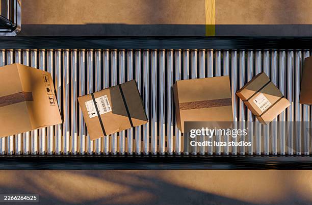 packages on roller conveyor in warehouse distribution center ready for shipping and logistics processing - verpakking stockfoto's en -beelden