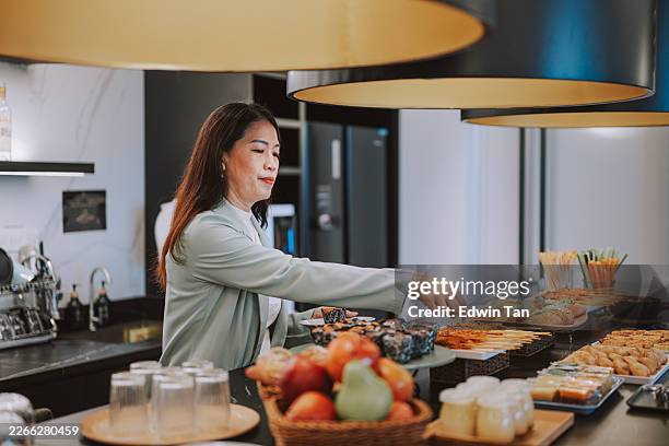 femme d’affaires asiatique choisissant des plats dans un buffet dans un salon moderne - restaurant chinois photos et images de collection