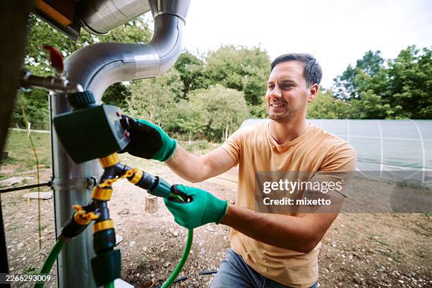 young man connecting water hose for irrigation system - sprinkler installation stock pictures, royalty-free photos & images