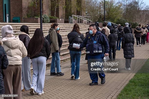Campus security guard hands out face masks to staff and students queueing to receive antibiotics at the University of Kent in Canterbury after an...