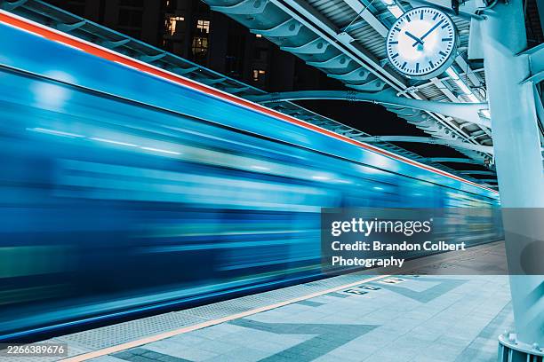 motion blurred train passing through modern urban transit station at night - underground train stock pictures, royalty-free photos & images