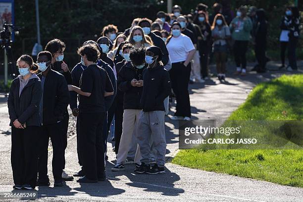 Students wearing face masks queue up to get vaccinated at the University of Kent in Canterbury, south-east England on March 18 following an outbreak...
