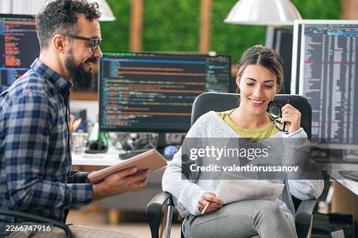 Software engineers collaborating on program coding in modern office Software engineers collaborating on program coding in modern office