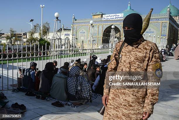 Taliban security personnel keeps watch as Afghan Muslims offer Eid al-Fitr prayers, which marks the end of the holy fasting month of Ramadan, at the...