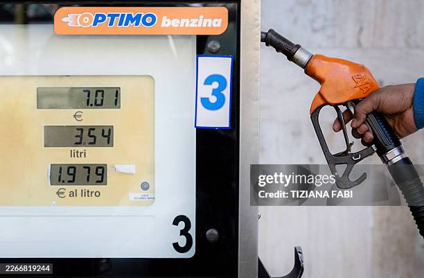 Man grabs the gas pump pistol at a gas station in Rome on March 19, 2026. Italy on March 18, 2026 adopted by decree measures to reduce fuel prices in...