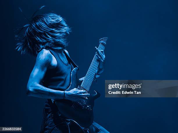 asian male rock guitarist performing on stage with electric guitar - gitarist stockfoto's en -beelden