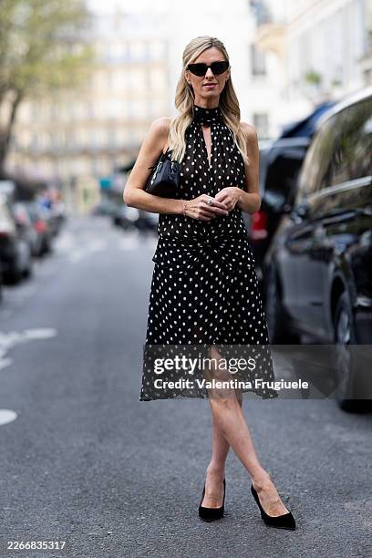 Nicky Hilton wears black pumps, a silver bracelet, a silver rings, silver bow earrings, a black bow in the head, black Miu Miu sunglasses, a black...