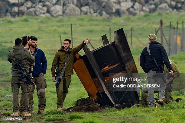 Israeli security personnel secure an area around a rocket partly buried in a field in the Israeli-annexed Golan Heights bordering Lebanon, on March...