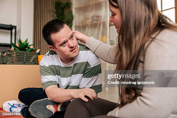 couple with down syndrome sitting on floor and talking in new apartment - developmental disability stock pictures, royalty-free photos & images