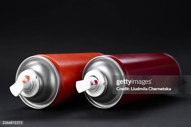 Two spray paint cans on dark gray background, closeup