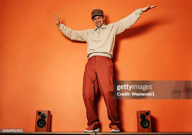 dancing man in vintage style with music speakers against orange wall - solo un uomo di età media foto e immagini stock