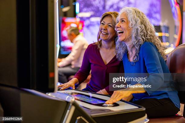 mature women looking very happy playing in the slot machines at a casino - coin operated stock pictures, royalty-free photos & images