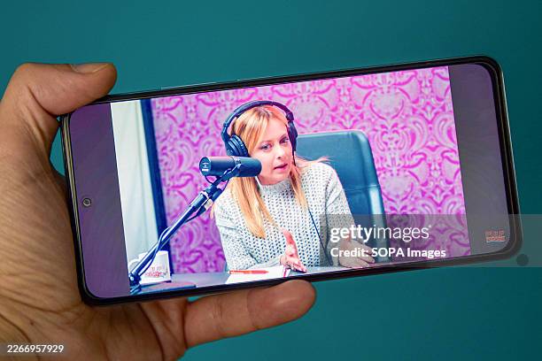 In this photo illustration, a smartphone displays, Italian Prime Minister Giorgia Meloni on rapper Fedez's 'Pulp Podcast' with co-host Mr. Marra ....