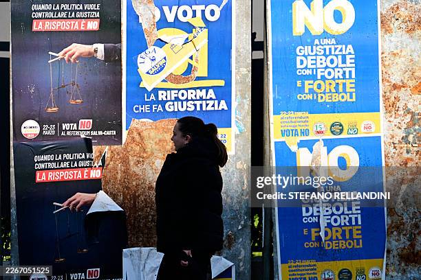 Person walks past campaign posters to promote the "NO" to the upcoming referendum on Justice reform, on March 20, 2026. Italian citizens will vote on...