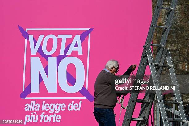 Man works next to a giant poster reading "Vote No to the law of the strongest" prior a campaign meeting of Elly Schlein, secretary of the Democratic...