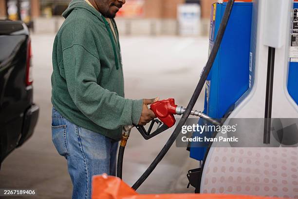 hombre repostando vehículo en la gasolinera - inflación fotografías e imágenes de stock