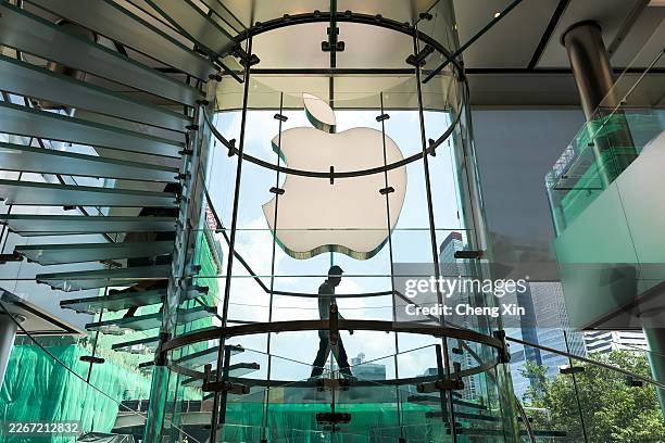 Man walks down a spiral glass staircase inside an Apple Store beneath the iconic Apple logo on March 18, 2026 in Hong Kong, China. Apple continues to...