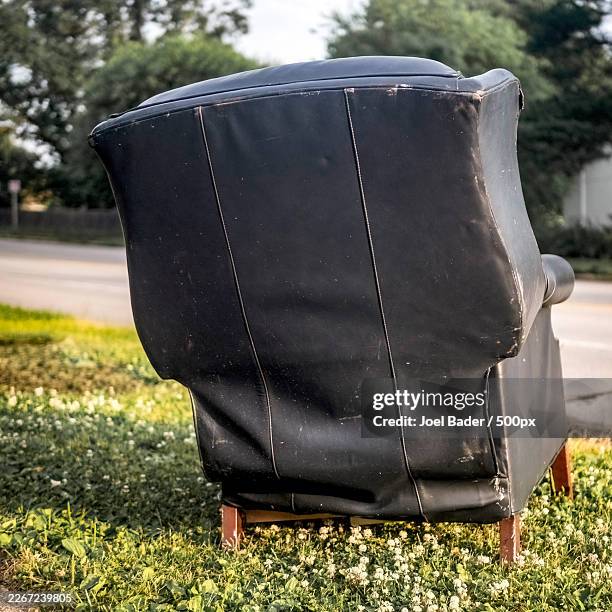 abandoned black armchair by the side of a road, with green grass and trees in the background,west des moines,united states,usa - curb stock pictures, royalty-free photos & images