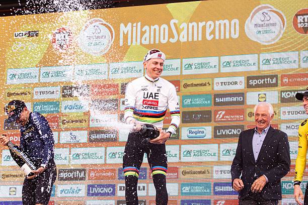 Thomas Pidcock, Tadej Pogacar, and Wout Van Aert celebrate on the podium during the champagne spraying at Via Roma in Sanremo, Italy, on March 21...