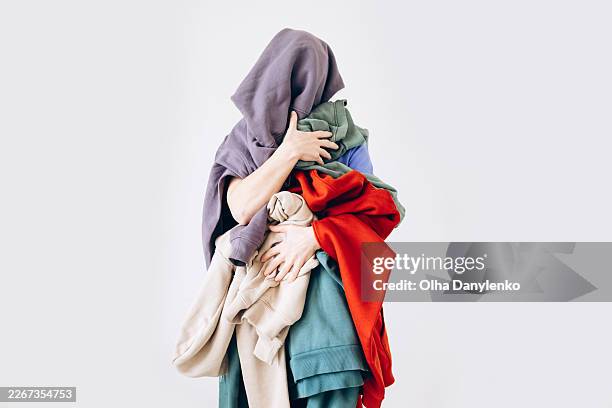 person overwhelmed holding pile of colorful clothes on white background - emotional series stock pictures, royalty-free photos & images