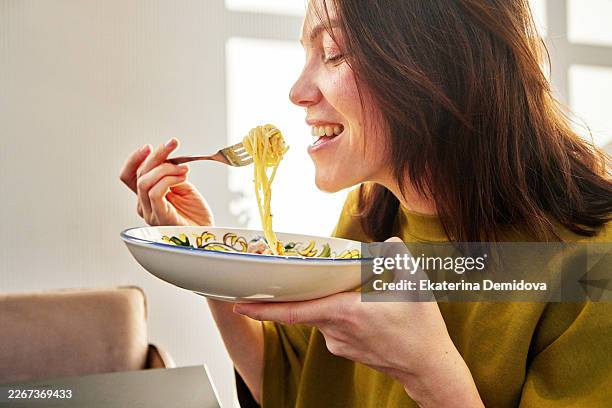 young woman enjoying delicious spaghetti pasta meal - carbohidrato fotografías e imágenes de stock