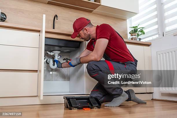 plumber working on kitchen sink water pipes - water pipe stock pictures, royalty-free photos & images